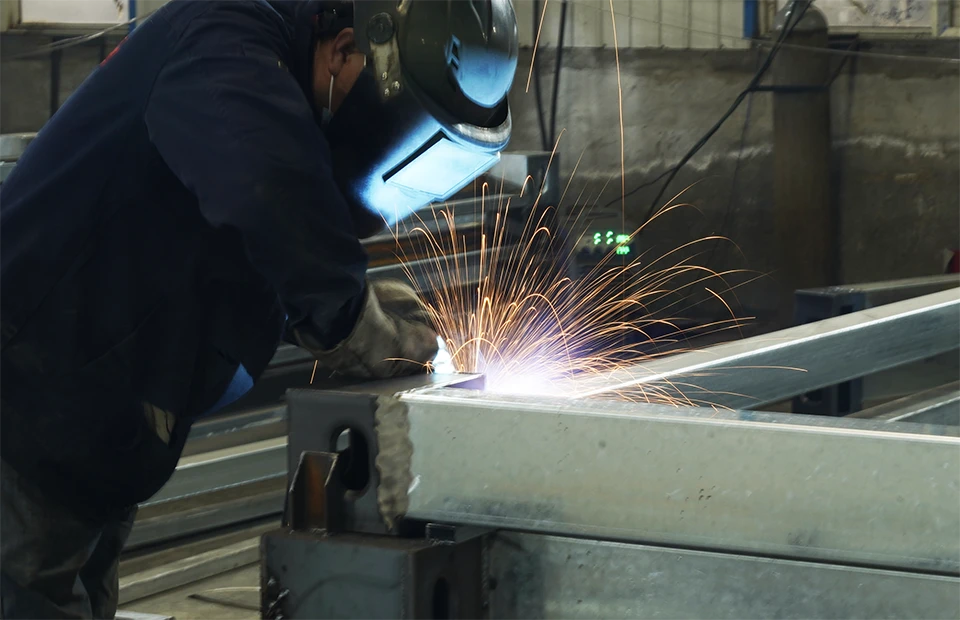 A worker is welding the footer of container house.